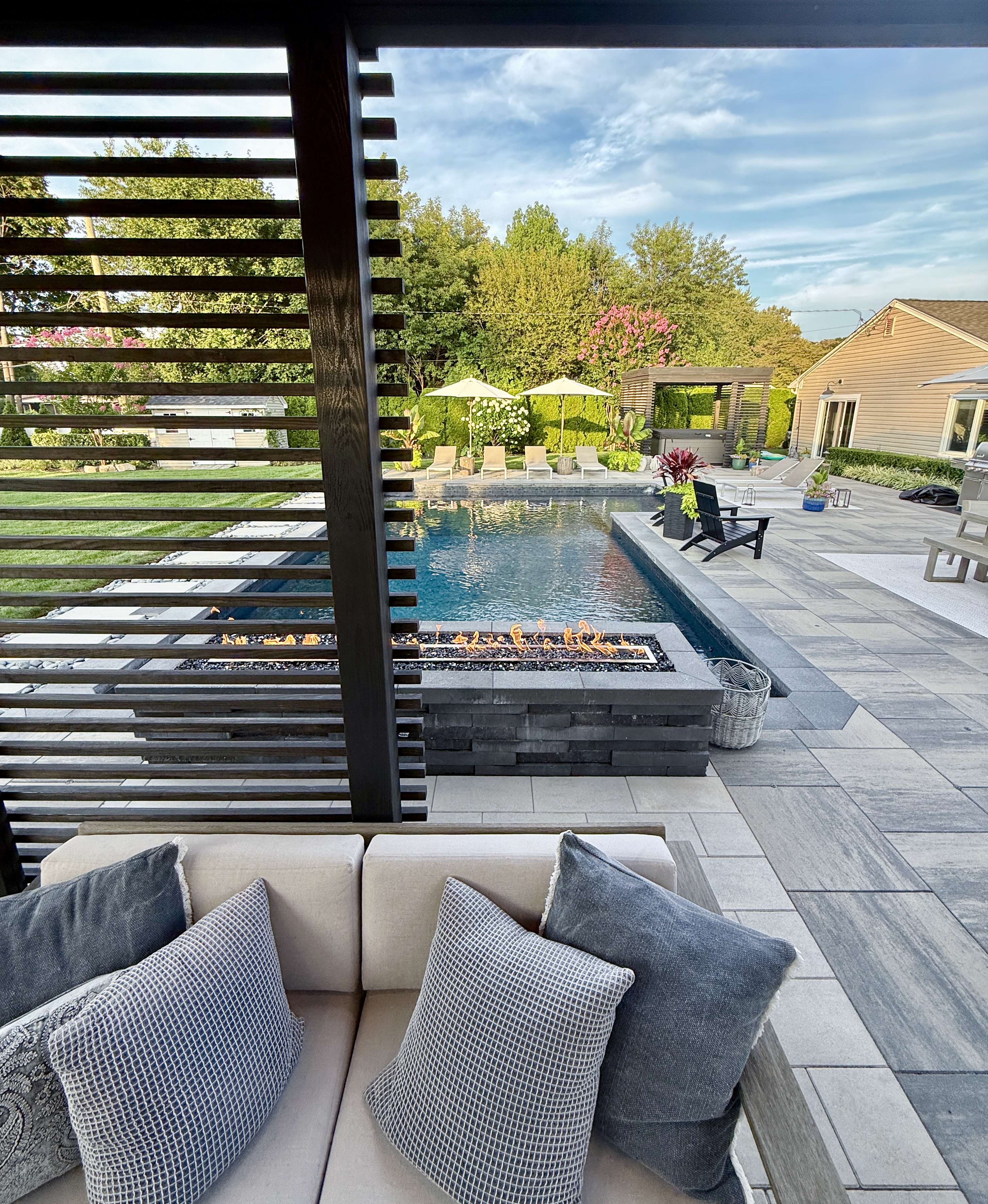Moderne graue Terrassenplatten aus Keramik rund um einen Pool im Garten