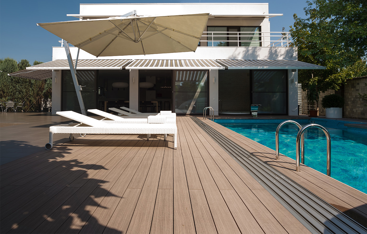 Terrasse mit Holzbelag und Pool, umgeben von stilvollen Gartenmöbeln.