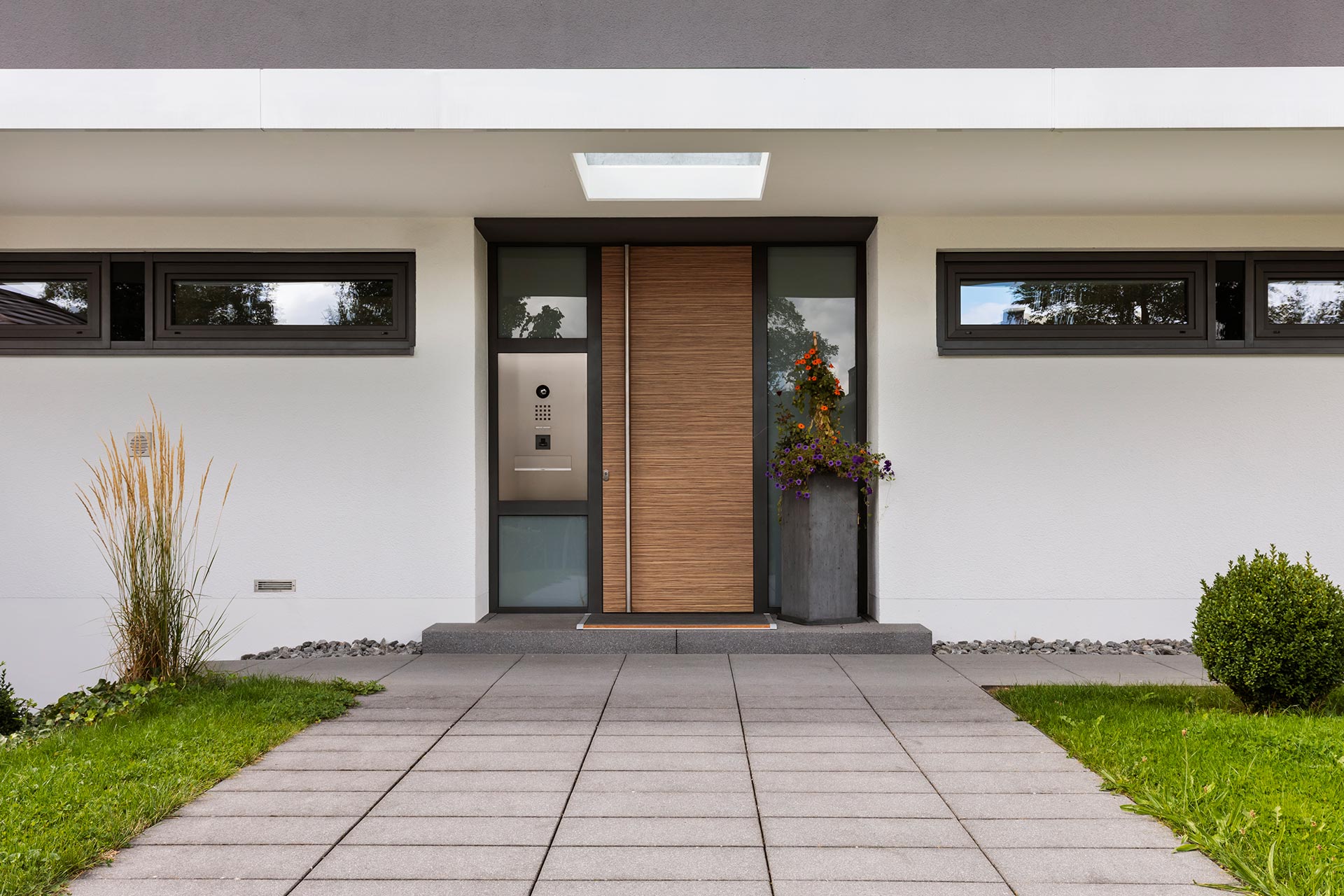 Moderner Hauseingang mit großflächiger Holzoptik-Tür und Glas-Elementen