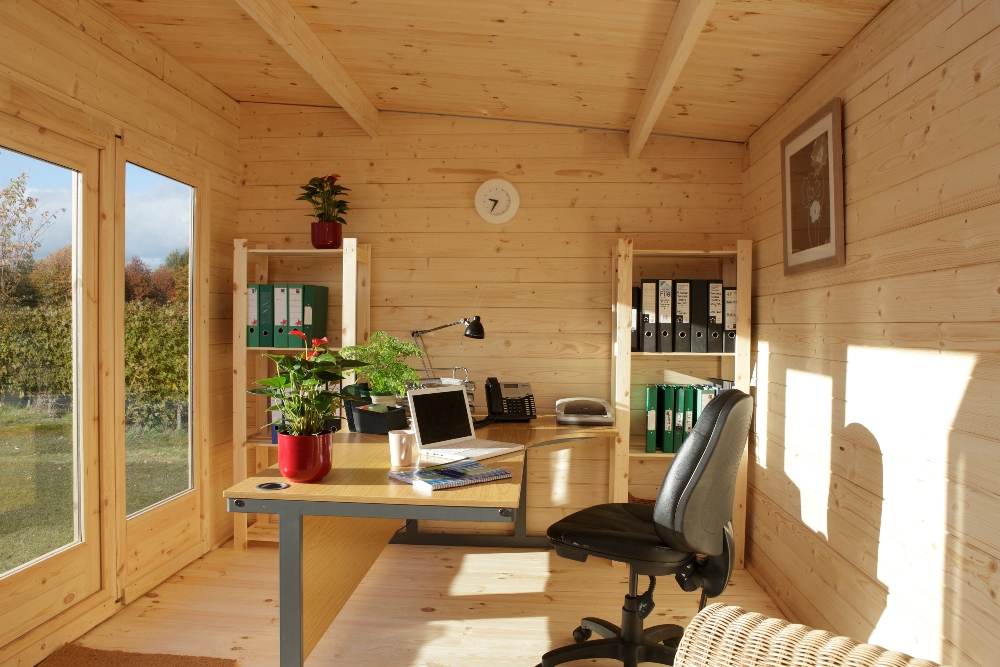 Innenansicht eines Garten-Office aus Holz mit Schreibtisch, Regalen und Tageslicht